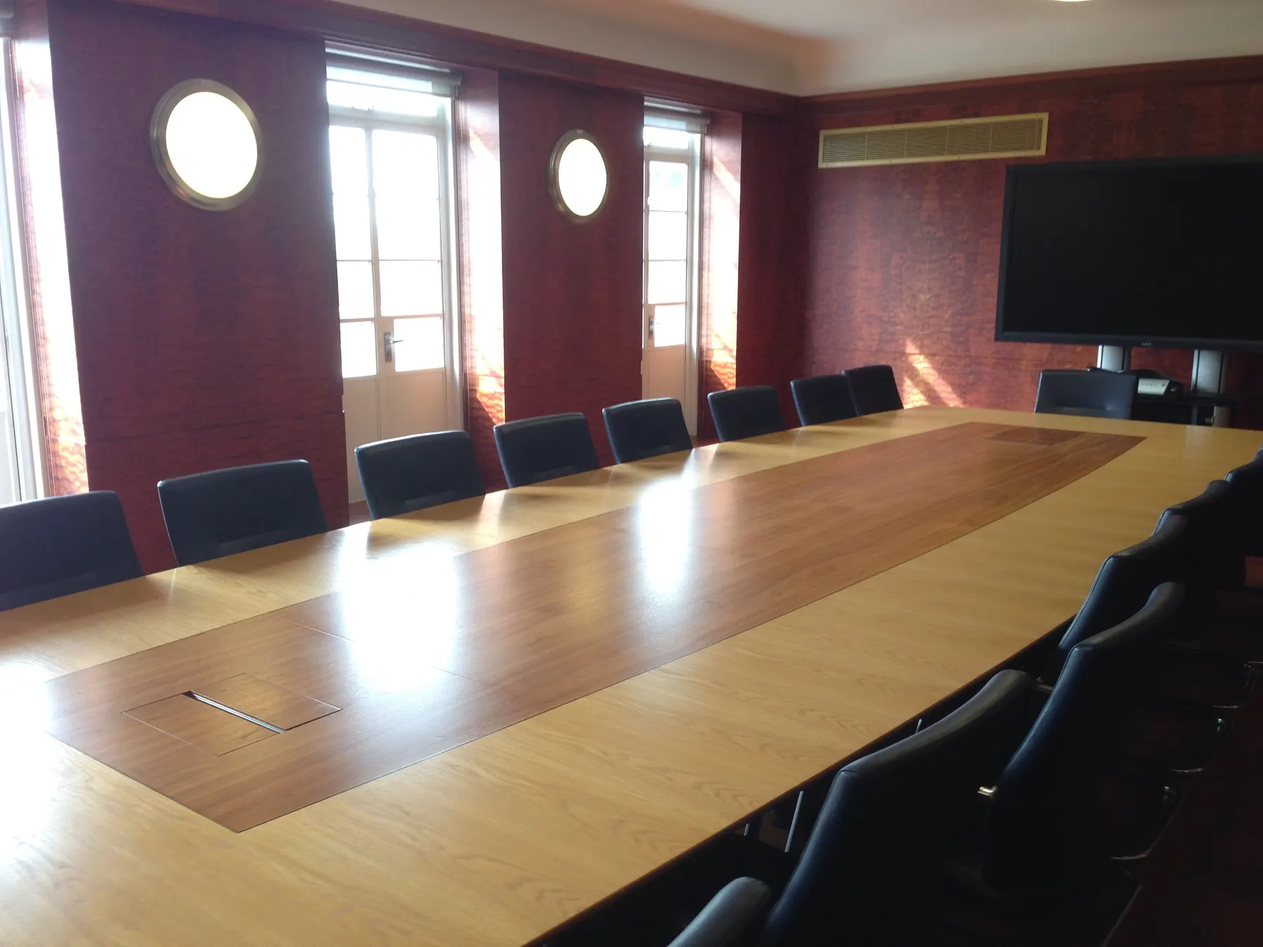 Sunlit conference room with a long wood table and leather chairs