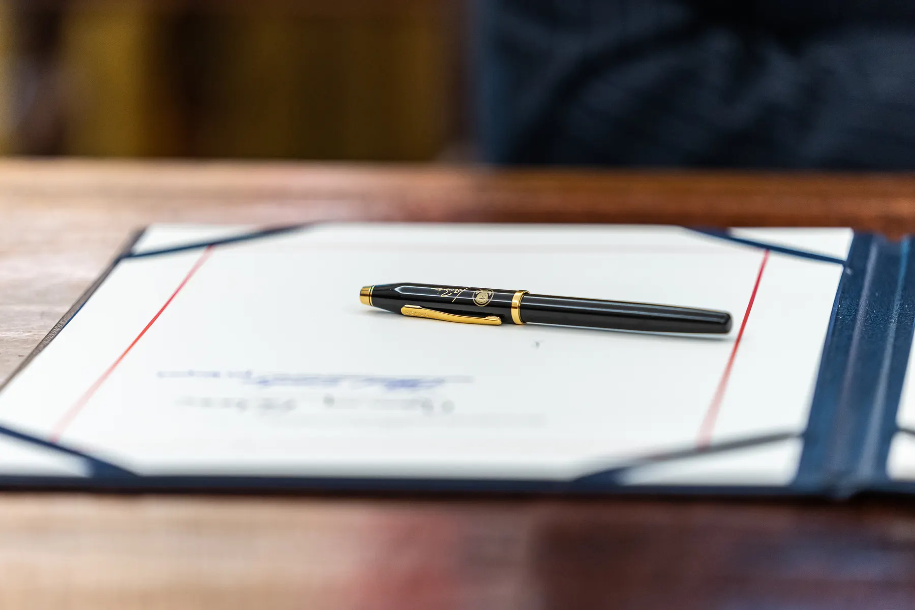 A pen resting on a signed document in a leather folder